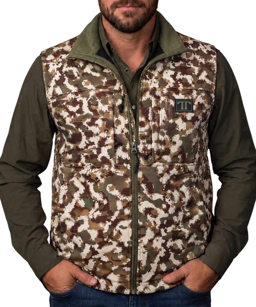 Front view of the men's camo Ferrell Brand vest featuring the mock collar, zip-up closure, zippered chest pockets, logo patch, and zippered hand pockets