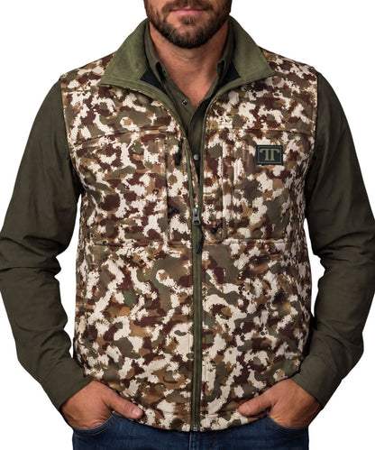 Front view of the men's camo Ferrell Brand vest featuring the mock collar, zip-up closure, zippered chest pockets, logo patch, and zippered hand pockets