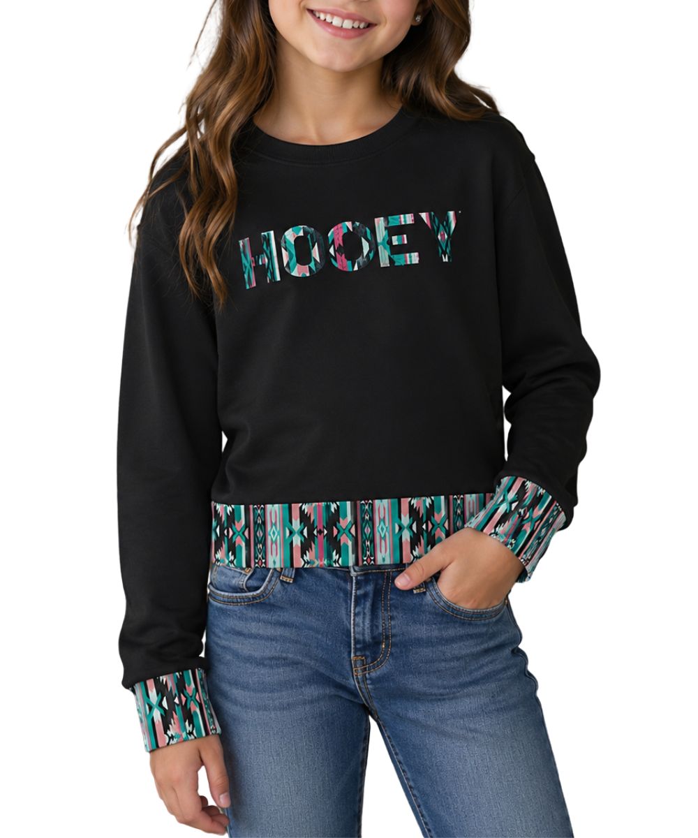 Model view of the girl's long sleeve crew neck pullover in charcoal featuring the southwestern-inspired logo on the front and contrast trim