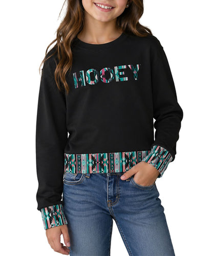 Model view of the girl's long sleeve crew neck pullover in charcoal featuring the southwestern-inspired logo on the front and contrast trim