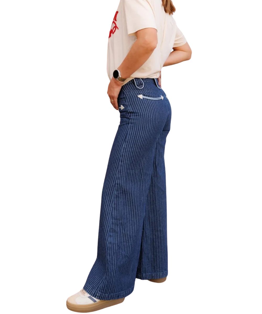 Side view of the women's blue denim jean featuring the wide leg, smiley pockets, white vertical pin striping, and the white piped trim on the belt loops