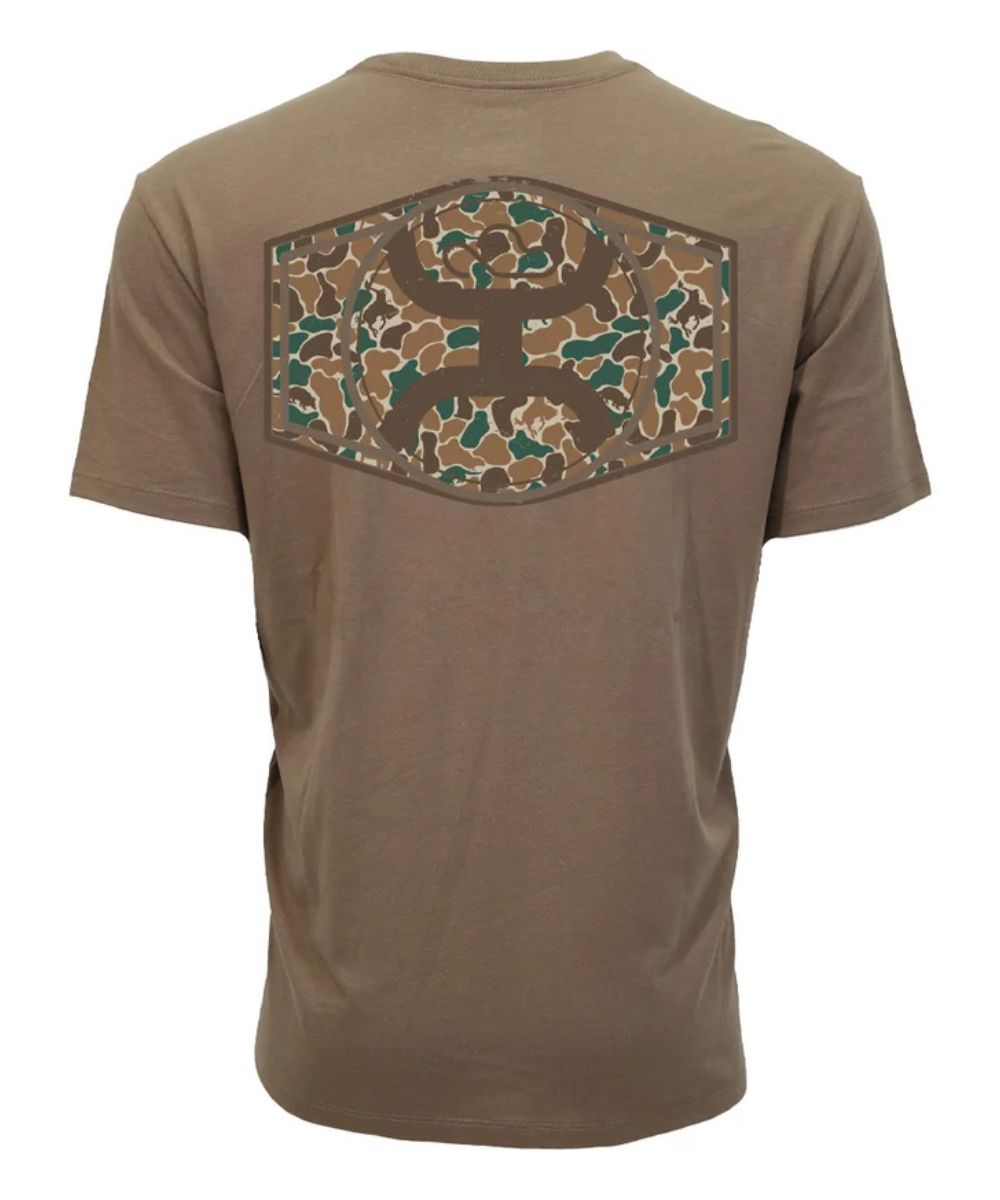 A brown short-sleeve t-shirt shown from the back, featuring a large hexagonal camouflage patch with a deer head silhouette in the center.
