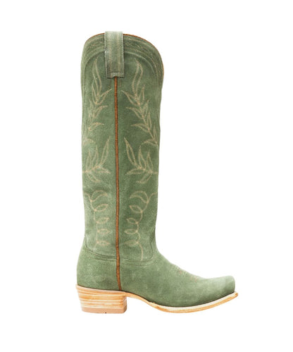 An olive green suede cowboy boot with beige floral embroidery on the shaft, a light brown wooden block heel, and a light tan leather pull tab, shown in profile against a white background.