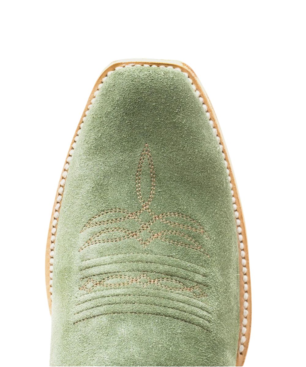 Close-up of a sage green suede boot toe with decorative stitching and a light tan sole edge on a white background.