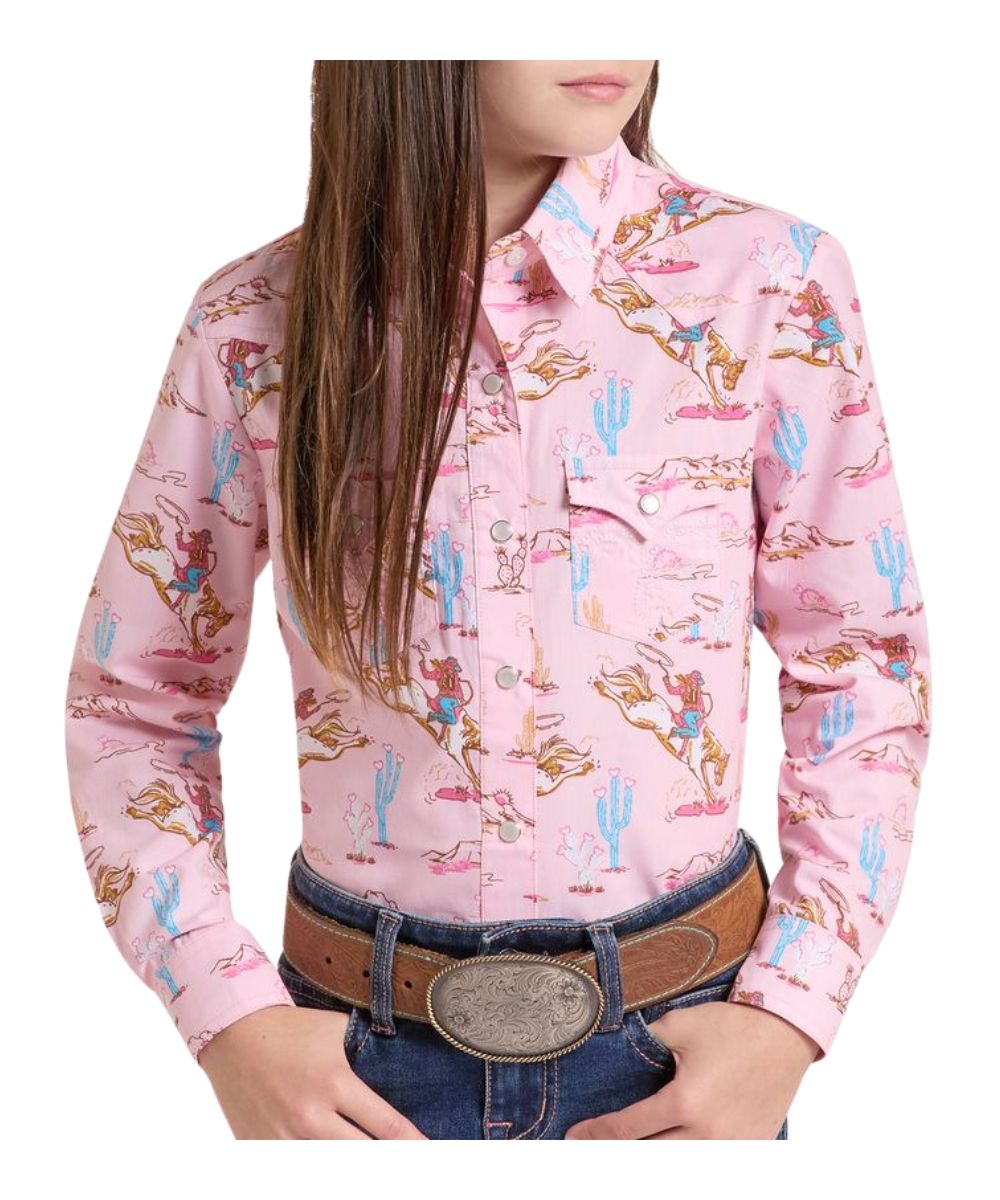 Front view of the girl's pink Panhandle long sleeve snap shirt featuring the cowgirl desert landscape print, snap flap chest pockets, spread collar, and western yokes
