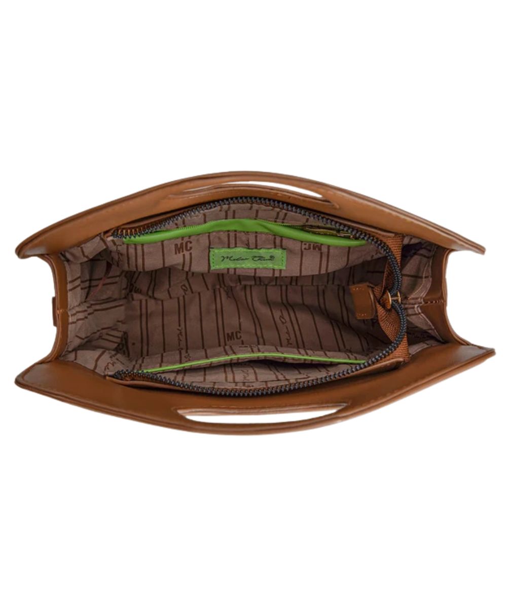 An open brown purse showing its interior lining with a brown monogram pattern, a bright green zipper track, open slip pocket, and a green interior label.