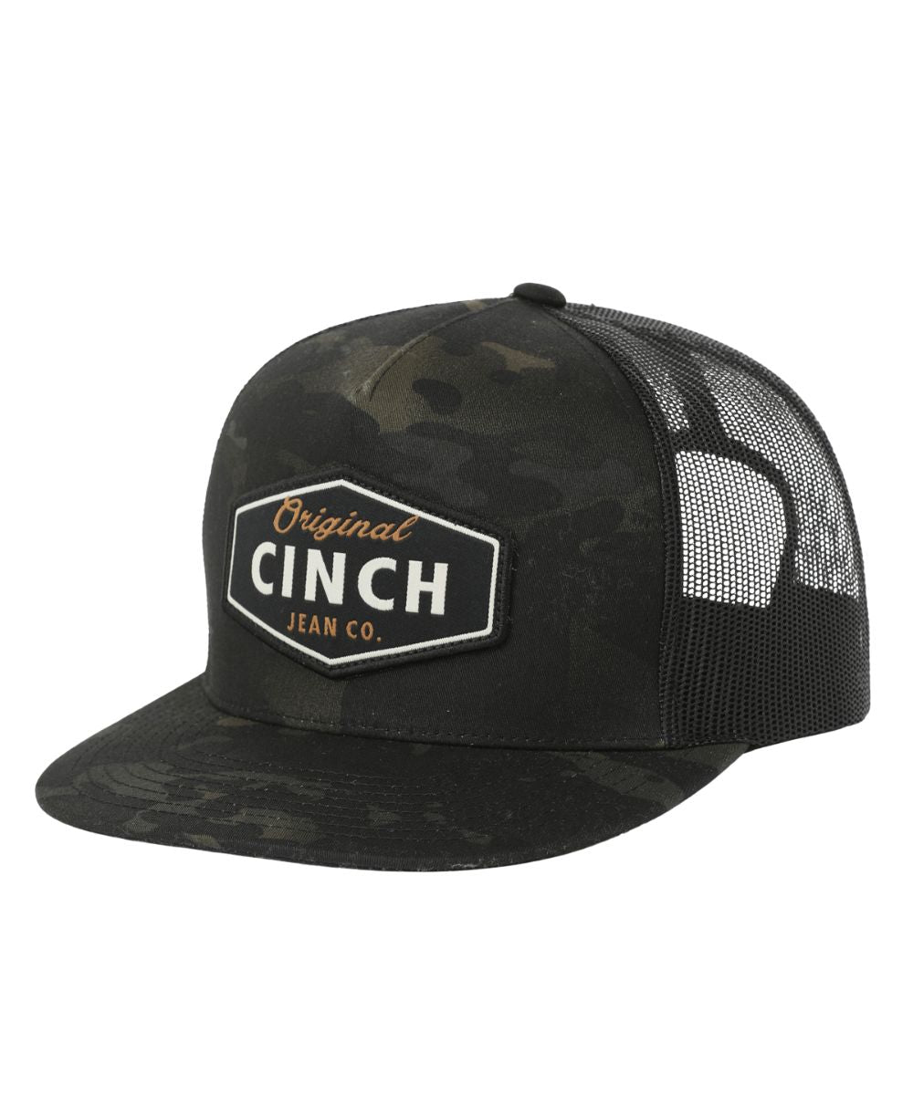 Left angled view of the men's black camo trucker cap featuring a woven logo patch on the front