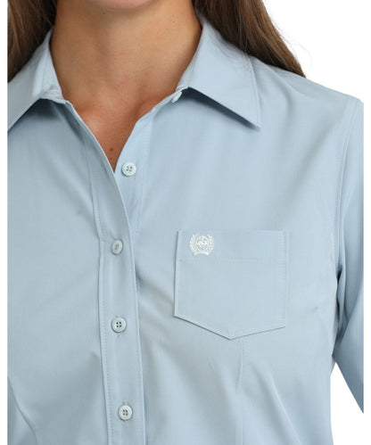 Close-up view of the women's solid print light blue button down shirt featuring the marble buttons and chest pocket