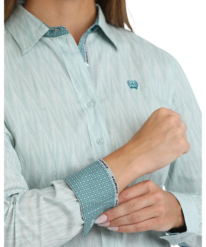 Close-up view of the light blue button down featuring the geometric print, logo embroidery on chest, and contrast interior trim
