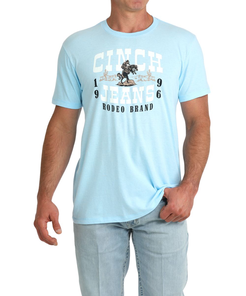 Men's Light Blue Graphic Tee With A Front Screen Print That Reads: "Cinch Jeans 1996 Rodeo Brand" And A Desert Cowboy Graphic