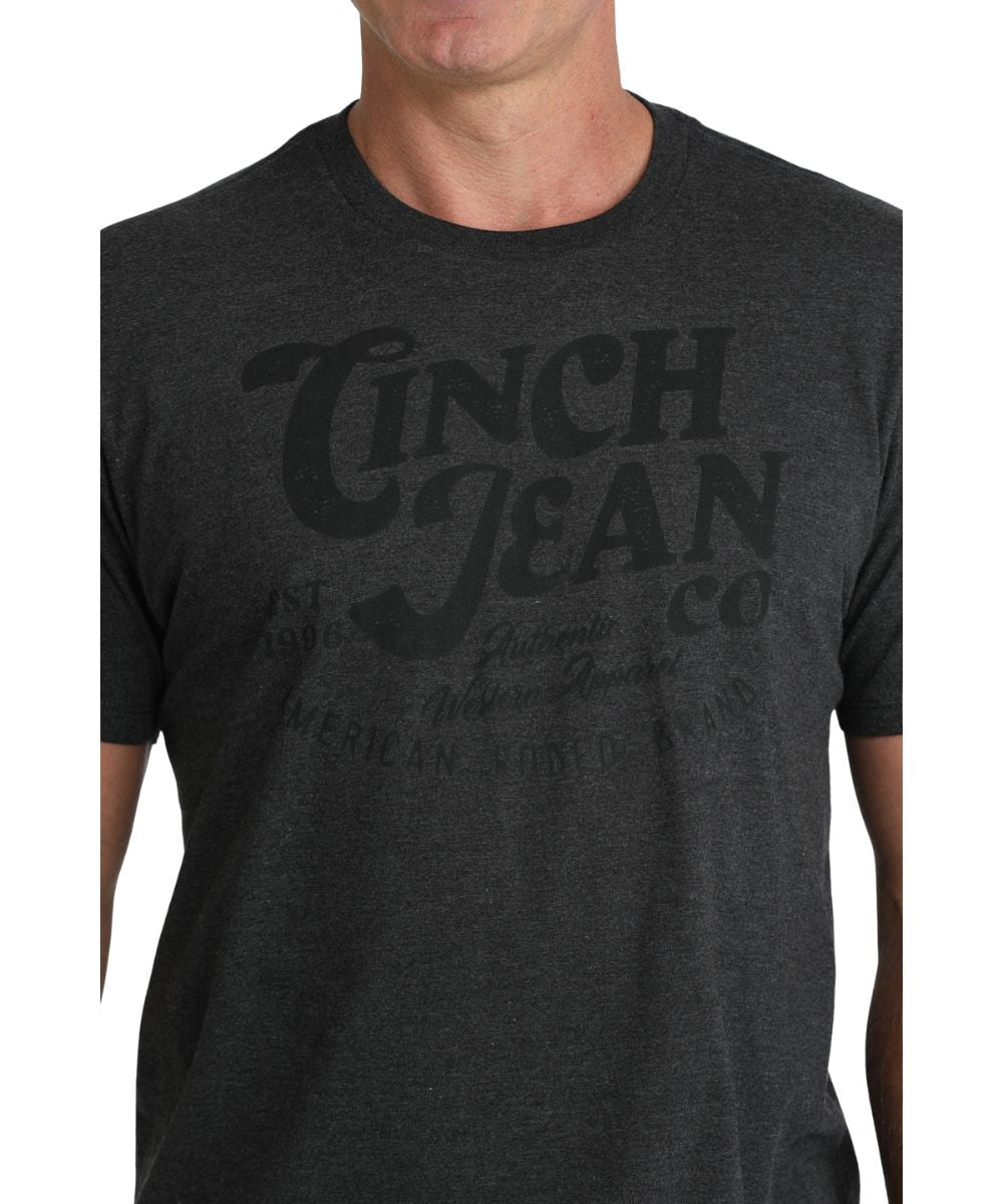 Close-up view of the front screen print reads: "Cinch Jean Co." on charcoal shirt