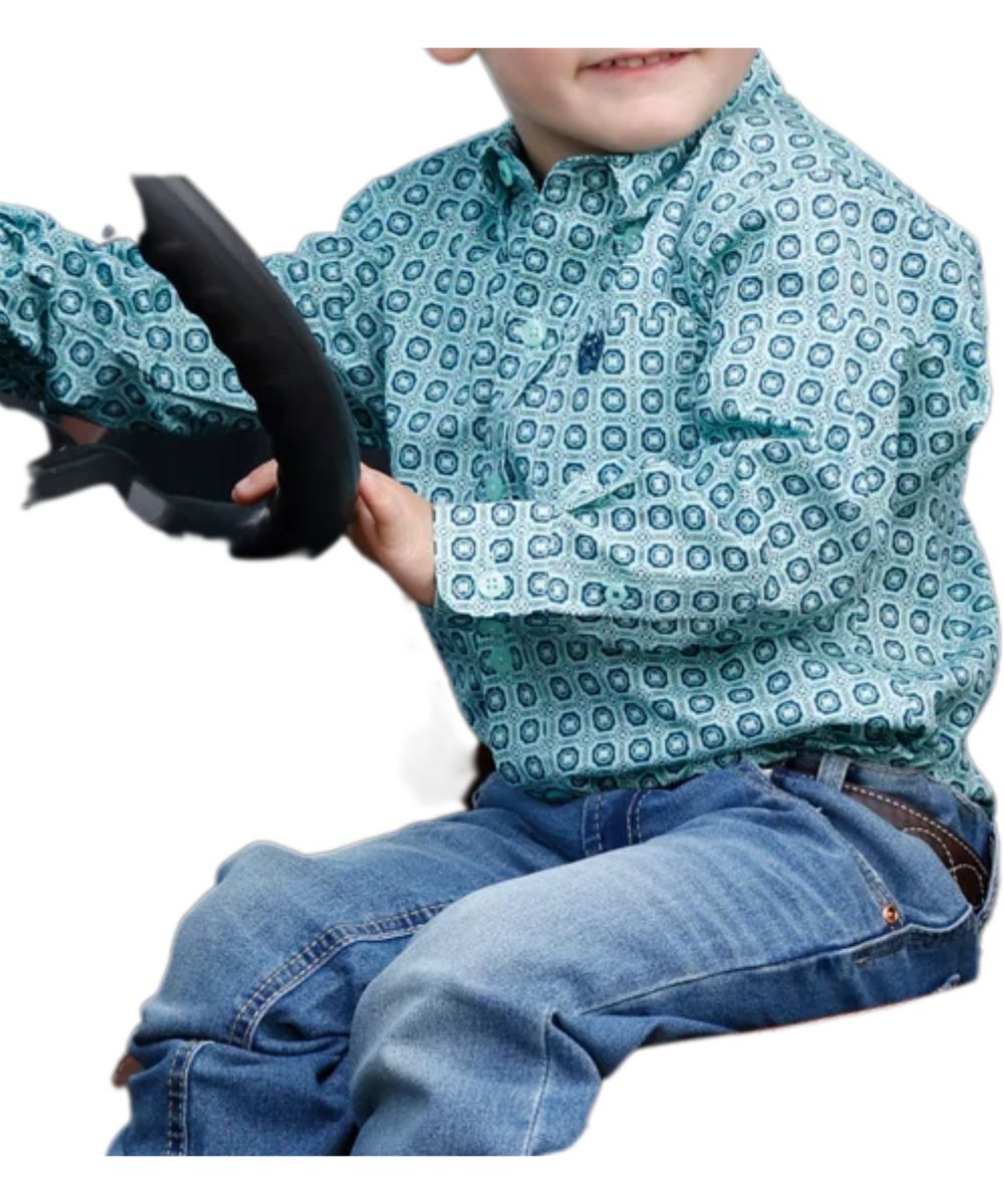 Side view of the toddler boy's turquoise Cinch long sleeve button down shirt featuring the button down collar, turquoise buttons, chest pocket, and geometric print