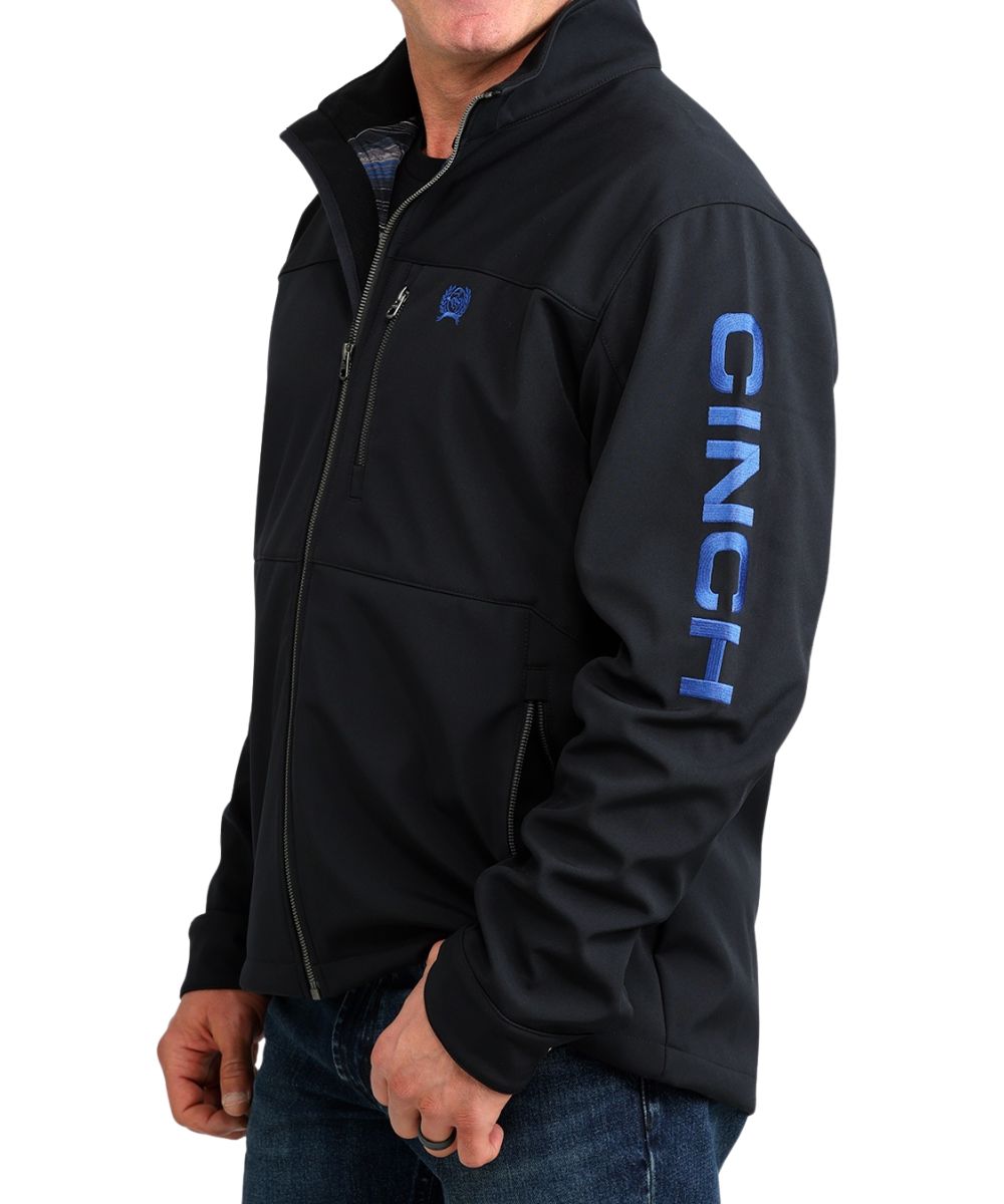 Side view of the men's black softshell jacket featuring the blue logo embroidery at the chest and left sleeve