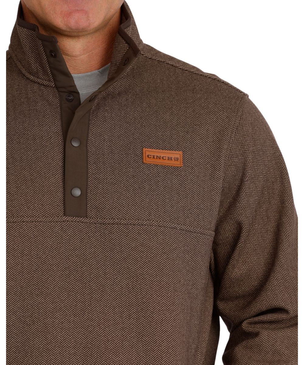 Close-up view of the sweater knit pullover featuring the leather logo patch, herringbone pattern, 1/4 snap placket, and mock collar