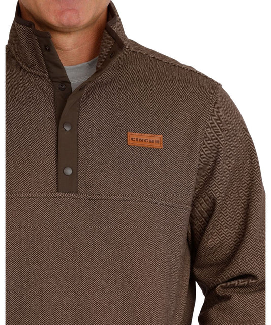 Close-up view of the sweater knit pullover featuring the leather logo patch, herringbone pattern, 1/4 snap placket, and mock collar