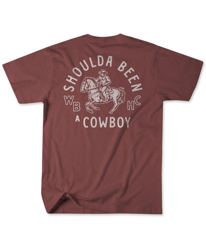 A maroon short-sleeve t-shirt shown from the back, featuring a distressed white graphic of a cowboy on a bucking horse with the text 'SHOULDA BEEN A COWBOY' and 'WBHC'.