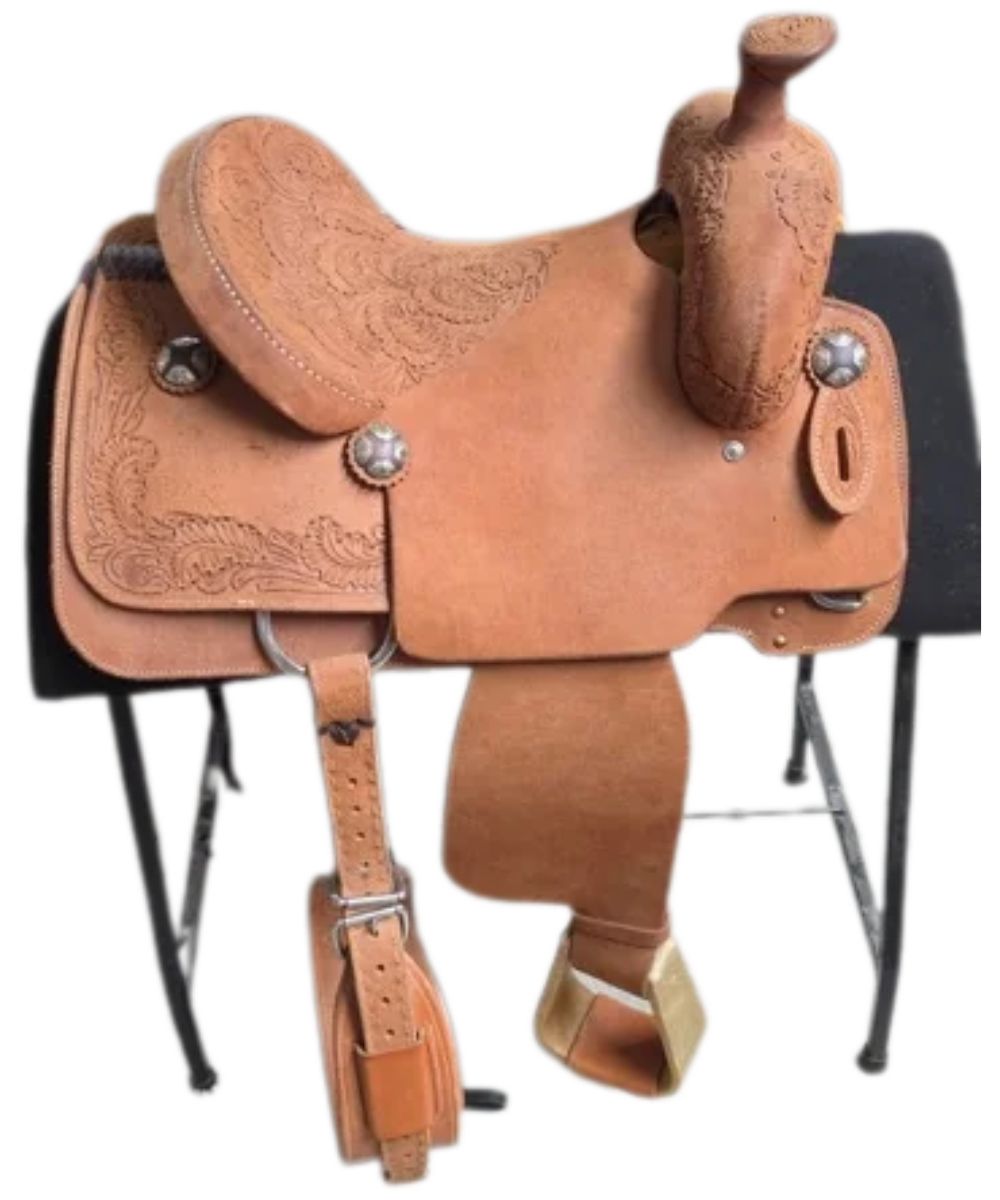 A classic western leather saddle in a warm tan/brown color, featuring intricate tooling and carved floral patterns. It is displayed on a black metal saddle stand against a plain white background.