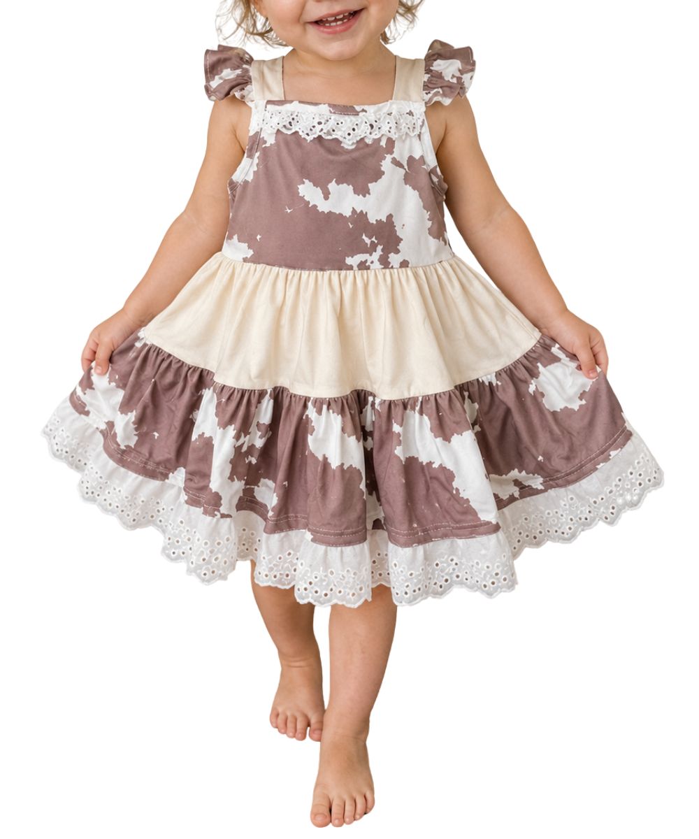 Front view of the girl's brown and white cow print ruffle dress featuring lace trim