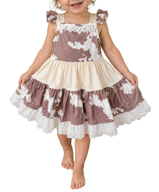 Front view of the girl's brown and white cow print ruffle dress featuring lace trim