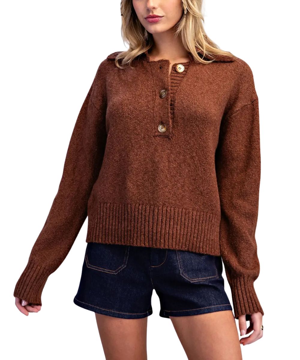 A woman wearing a brown knit sweater with a buttoned collar and dark blue denim shorts, shown against a plain white background.
