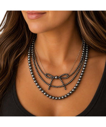 Model view of the women's faux navajo pearl layered necklace featuring the bow ribbon 