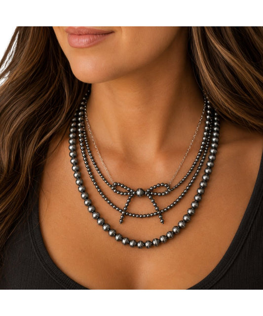 Model view of the women's faux navajo pearl layered necklace featuring the bow ribbon 