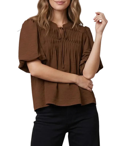 Front view of the women's brown She + Sky short sleeve blouse featuring the split v-neckline, puff sleeves, and pintuck detailing on the chest