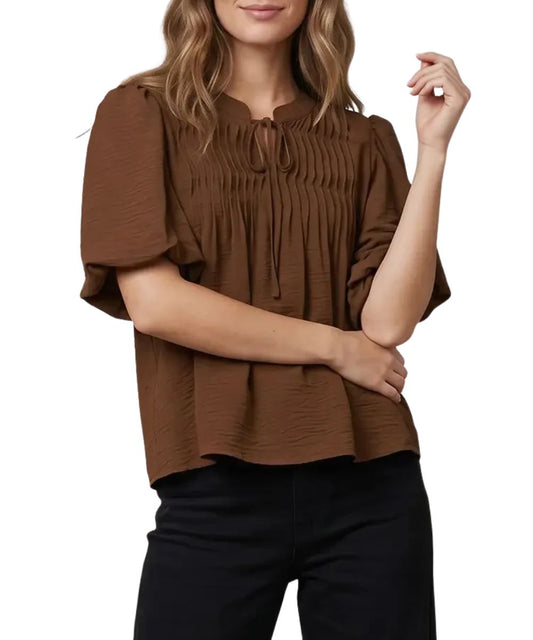 Front view of the women's brown She + Sky short sleeve blouse featuring the split v-neckline, puff sleeves, and pintuck detailing on the chest