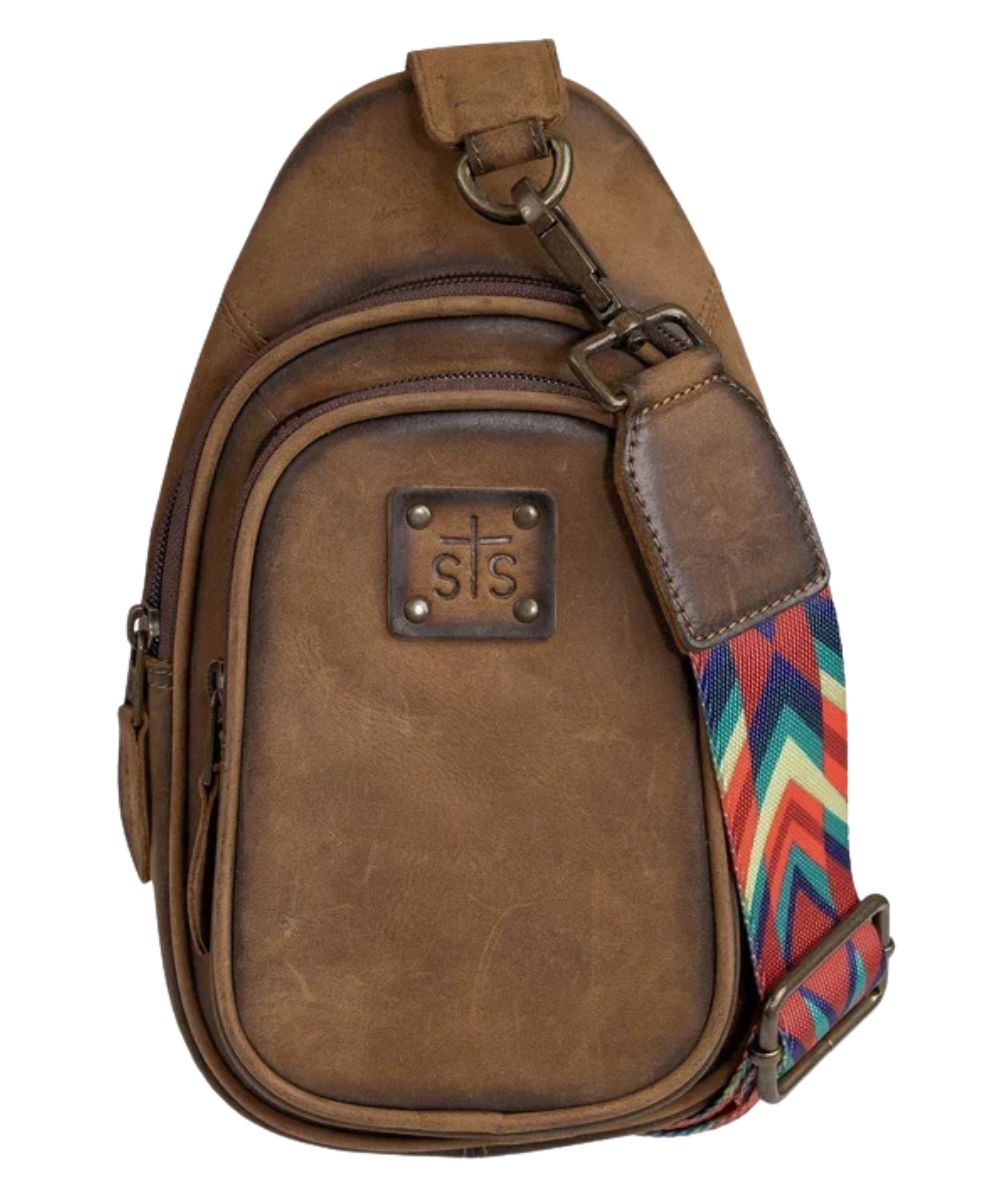 Front view of the women's brown STS Baroness Basic Bliss Sojourner Sling Bag featuring the STS stamped leather logo patch, dual zip compartments, and the printed nylon crossbody strap