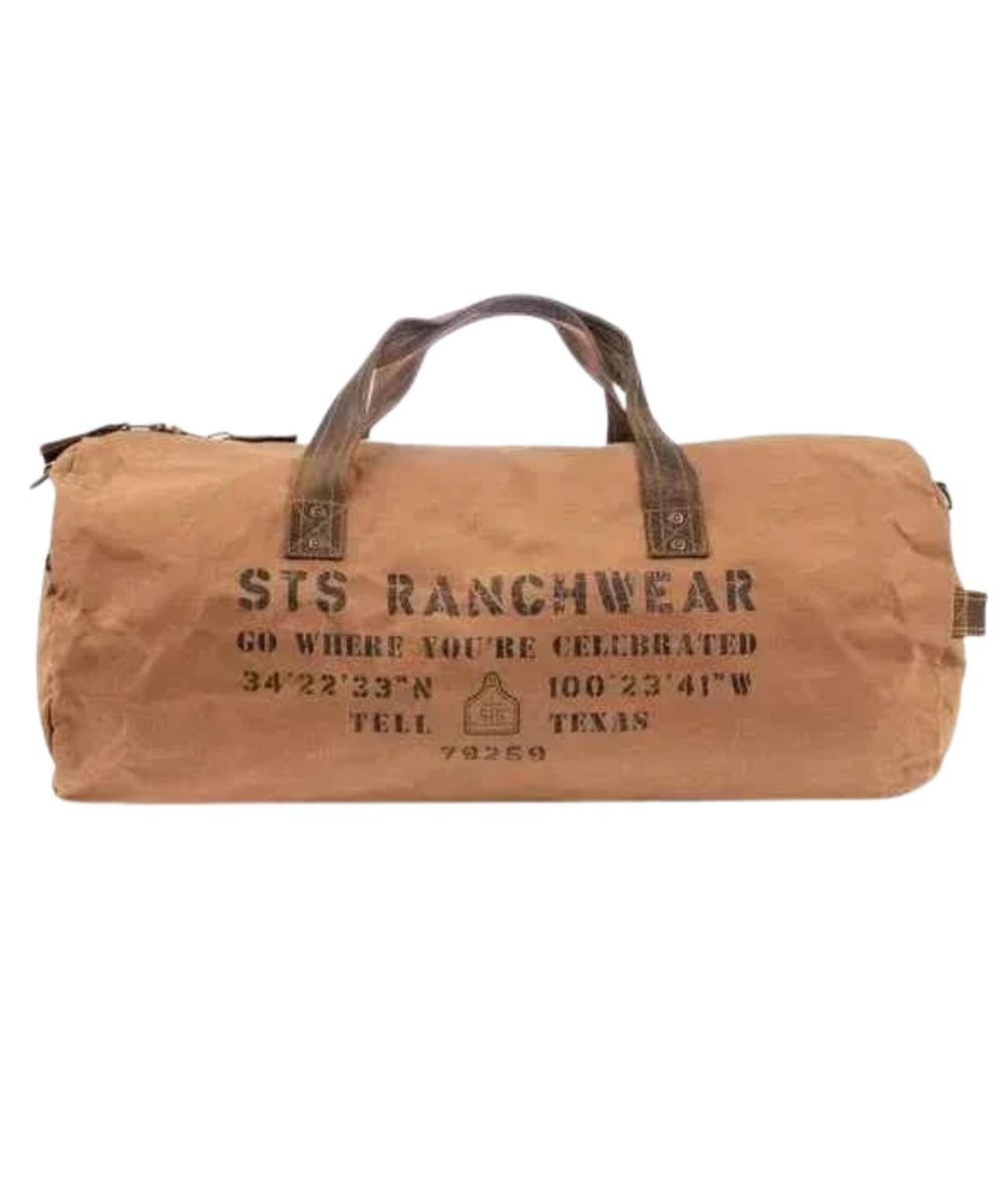 Front view of the tan canvas STS Ranch Surplus Duffle Bag featuring the genuine leather trim, an assorted STS Ranchwear print, a side leather carry handle, and the top leather carry handles
