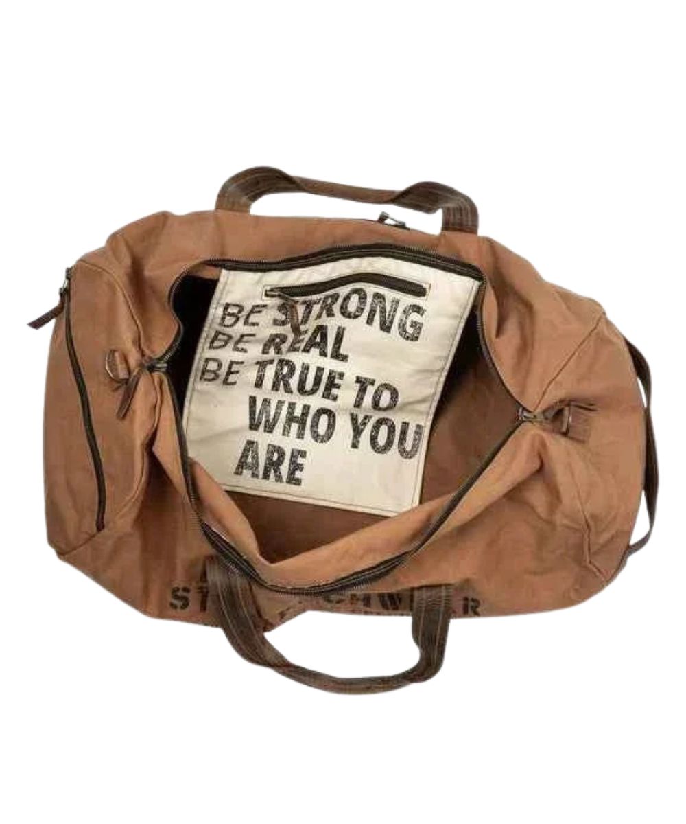 Interior view of the main compartment featuring the zip closure, an interior zip pocket, and a quote that reads: "Be Strong. Be Real. Be True To Who You Are."