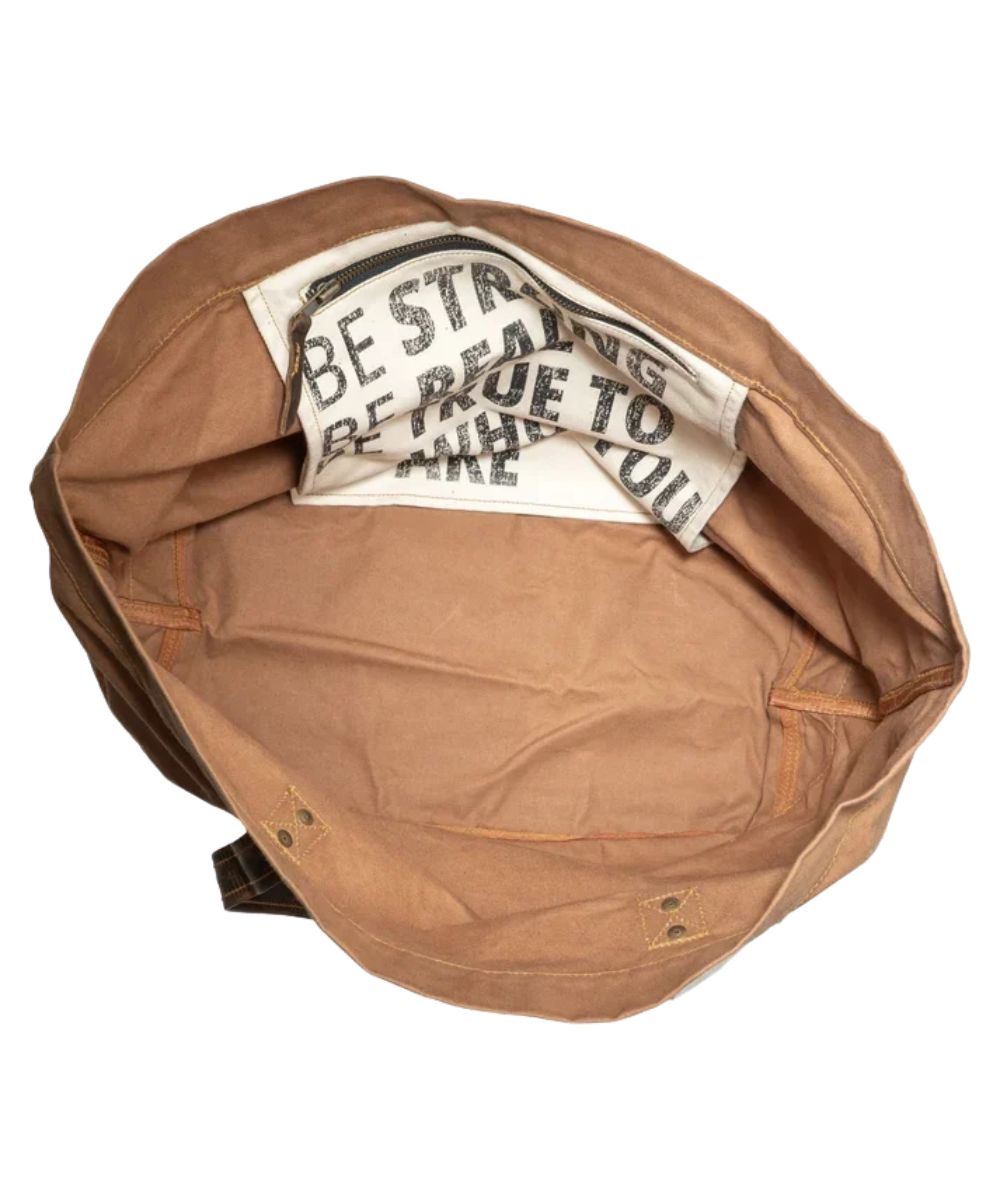 Interior view of the single main compartment with a interior zip pocket and an inside quote that reads: "Be Strong. Be Real. Be True To Who You Are."
