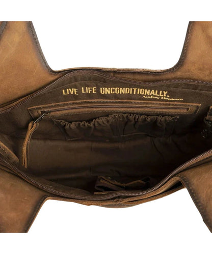 Interior view of the women's cowhide purse featuring the interior zip pocket, scrunch pockets, and a quote that reads: "Live Life Unconditionally."