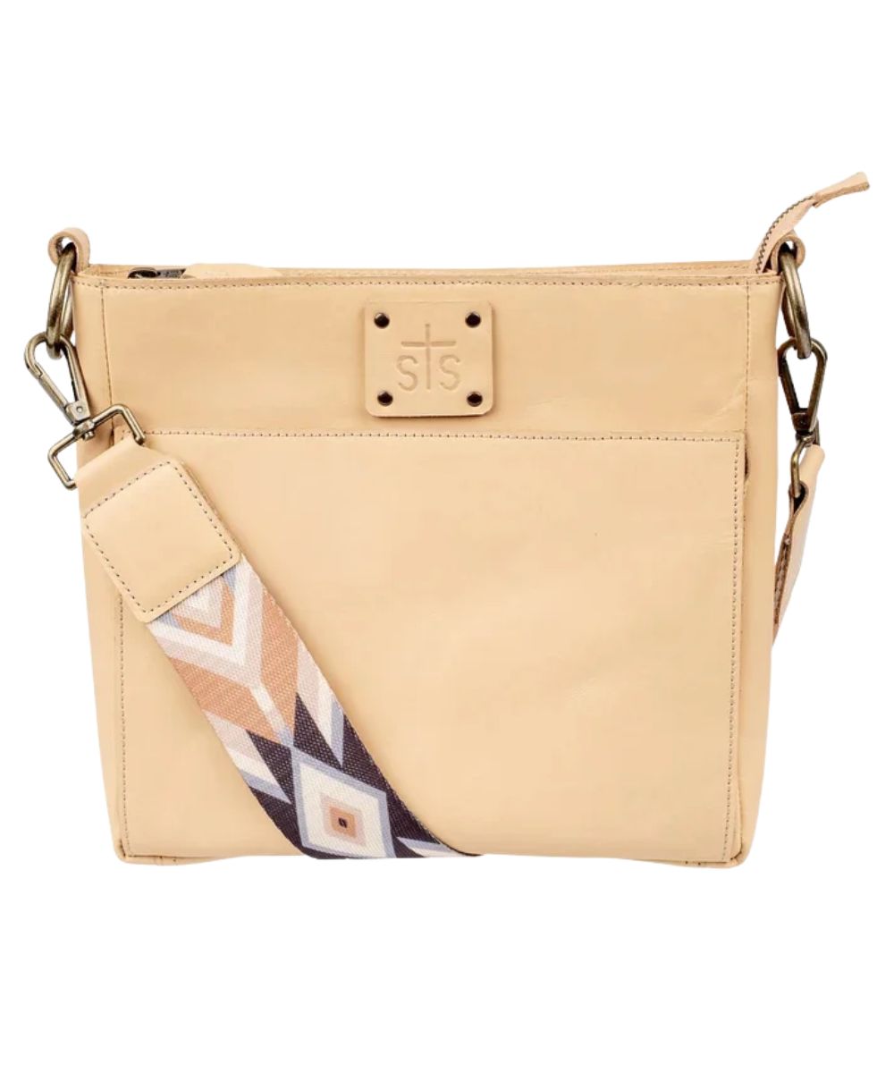 Front view of the women's beige STS Basic Bliss Buckskin Olivia Crossbody featuring the STS stamped leather patch and the printed nylon removable crossbody strap