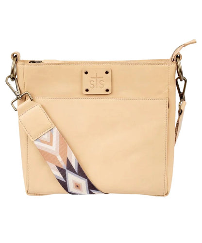 Front view of the women's beige STS Basic Bliss Buckskin Olivia Crossbody featuring the STS stamped leather patch and the printed nylon removable crossbody strap