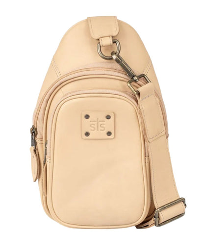 Front view of the women's beige STS Basic Bliss Buckskin Sojourner Sling Bag featuring the beige leather construction, STS logo patch, dual zip compartments, and the removable/adjustable beige leather shoulder strap