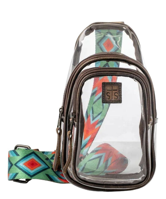 Front view of the women's clear STS Stadium Rules Sojourner Sling Bag featuring the dual zipper compartments, STS logo patch, vinyl construction with brown leather trim, and the printed adjustable nylon crossbody strap