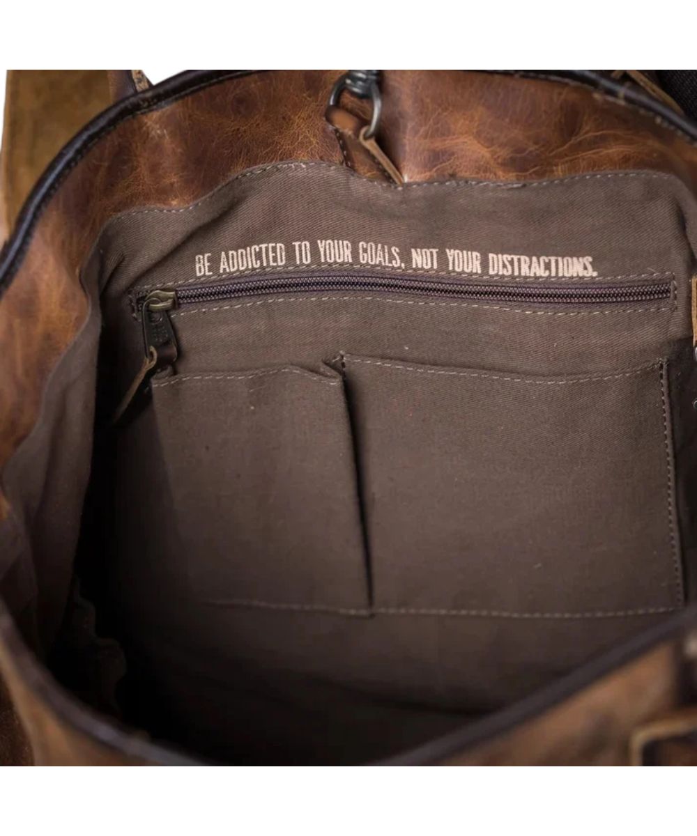 Interior view of the tote featuring the 2 slip pockets, zipper pocket, keychain clasp, and a quote that reads: "Be Addicted To Your Goals, Not Your Distractions."