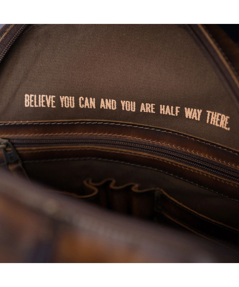 Interior view of the zip closure compartment featuring the zip pocket, scrunch pocket, pen slots, and card slots and a quote that reads: "Believe You Can And You Are Half Way There."