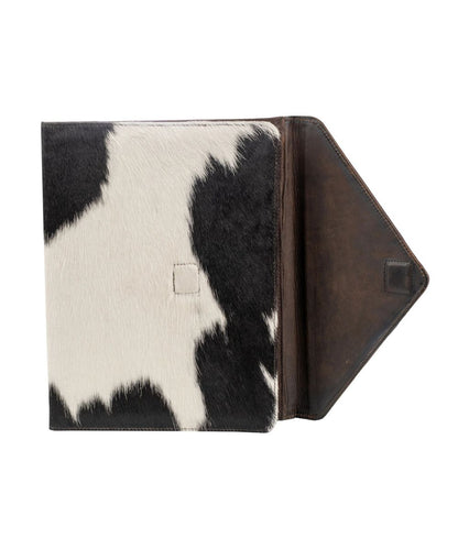 A tablet sleeve featuring a black and white cowhide pattern on the front cover and a dark brown leather interior flap, shown open against a plain white background.