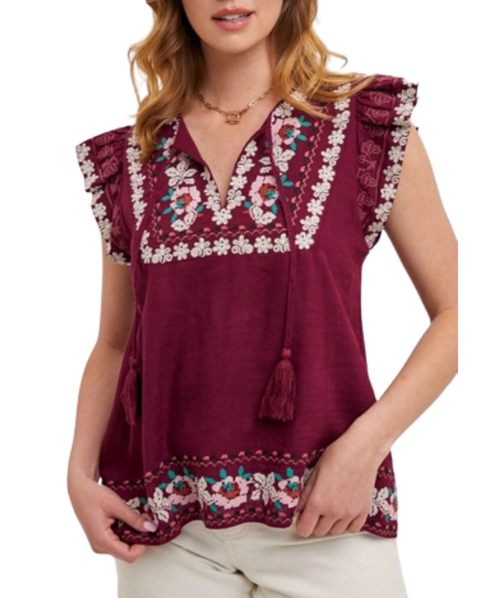 Front view of the women's plum boho top featuring intricate floral embroidery, a v-neckline with self-tie tassel strings, and short ruffled sleeves