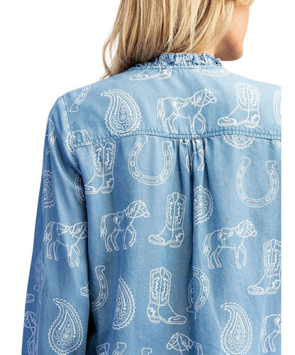 A close-up back view of a model wearing a light blue denim shirt with a white western-themed print featuring horses, boots, horseshoes, and paisley patterns.