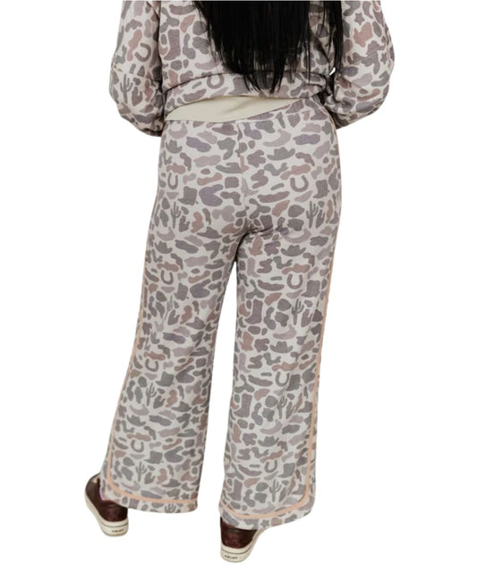Back view of the women's wide leg camo sweatpants with incorporated western motifs of cacti, horseshoes, and steer horns in neutral taupe, beige, and gray