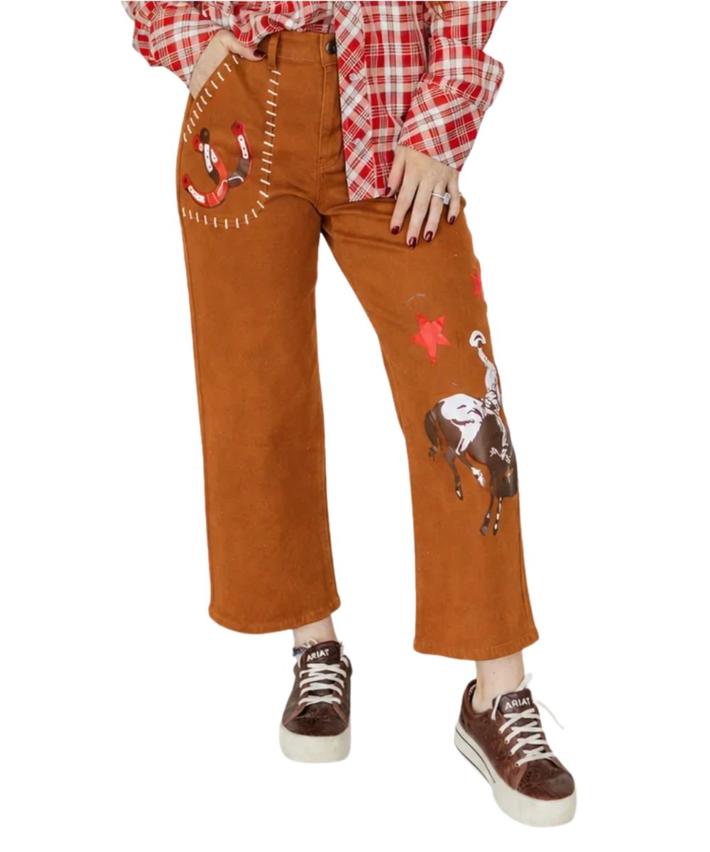 A person wearing rust-brown wide-leg pants with western embroidery, a red-and-white plaid shirt, and brown sneakers against a plain white background.