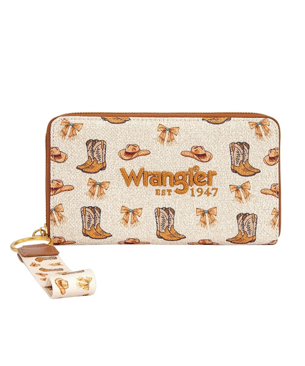 A Wrangler zip-around wallet in a cream canvas fabric with a brown leather trim and an allover print of cowboy boots, hats, and bows, featuring the 'Wrangler Est. 1947' logo on the front and a matching wristlet strap.