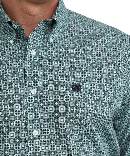 Close up view of single open pocket with Cinch embroidered logo and of button down collar of green and white geometric print shirt